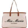 a white canvas bag with a brown leather handle