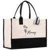 A beige tote bag with a black and white floral design and the name "Manny" printed on it.