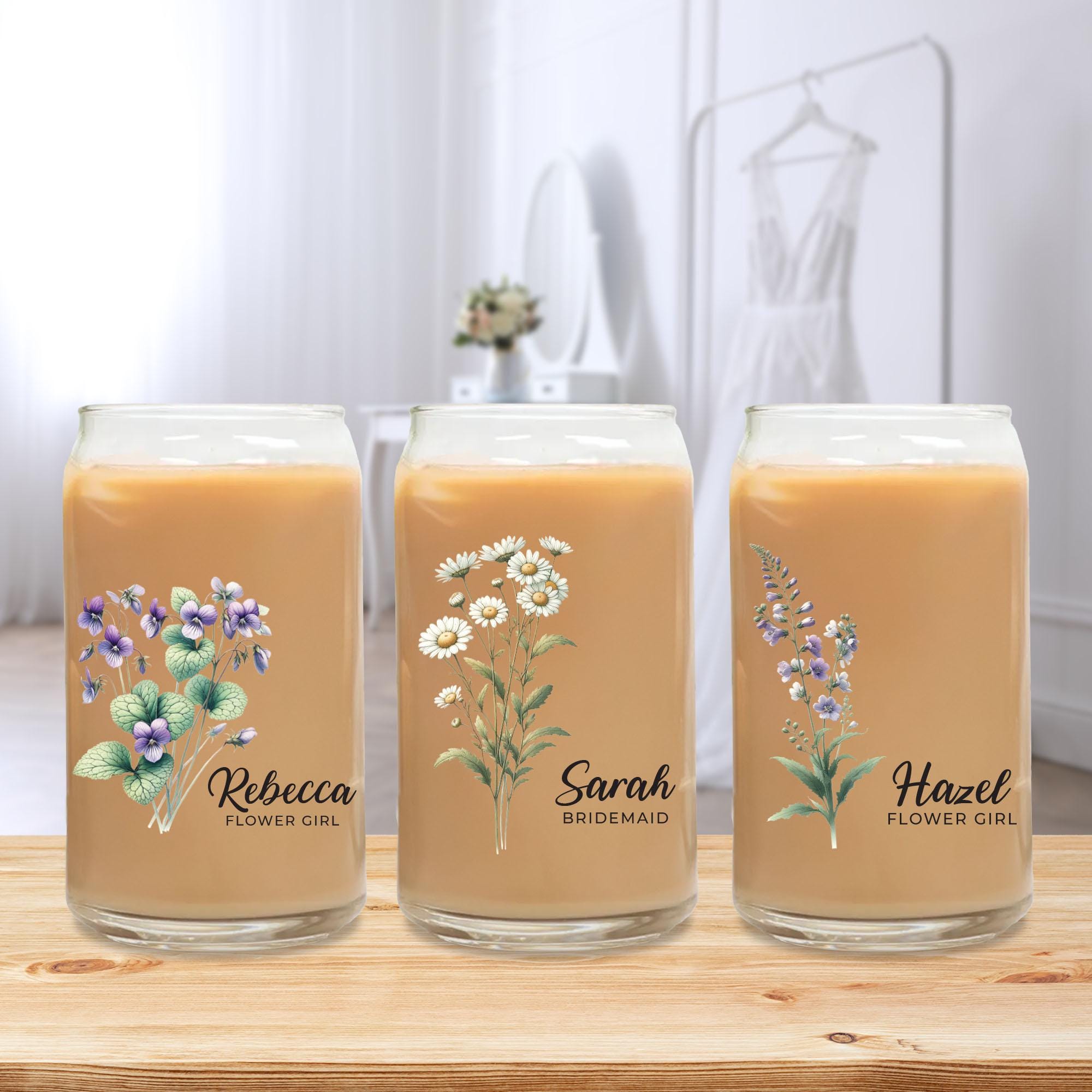 three jars with flowers on them sitting on a table