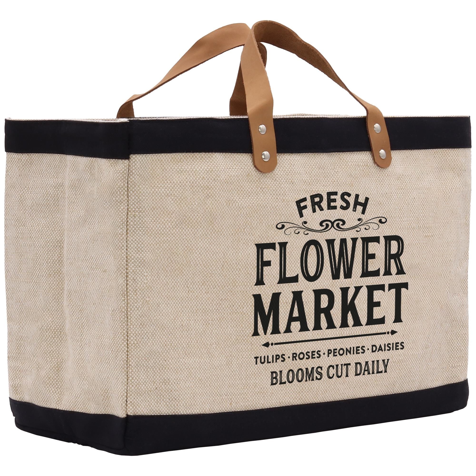 A beige canvas tote bag with black trim and leather handles, featuring the text &quot;FRESH FLOWER MARKET&quot; printed on it.