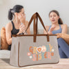 two women sitting on a couch, with a large tote bag with the text "GROovy Sister" printed on it in the foreground.