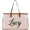 A beige canvas tote bag with the name "Lucy" printed in black cursive text on it.