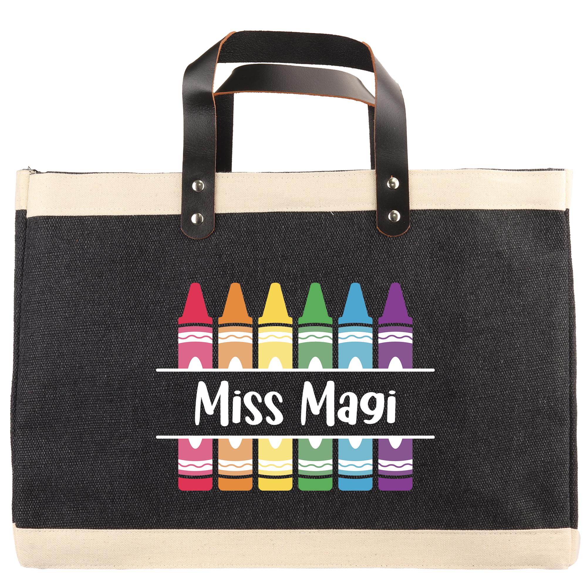 A black tote bag with a handle and a printed design of crayons in various colors.
