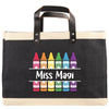 A black tote bag with a handle and a printed design of crayons in various colors.