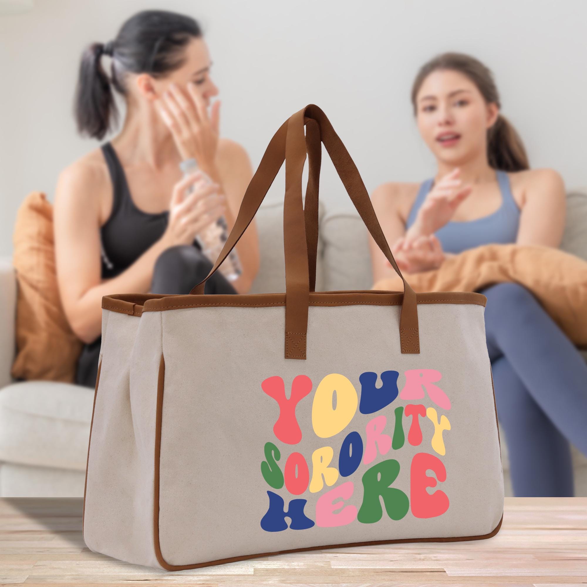 two women sitting on a couch with a canvas bag