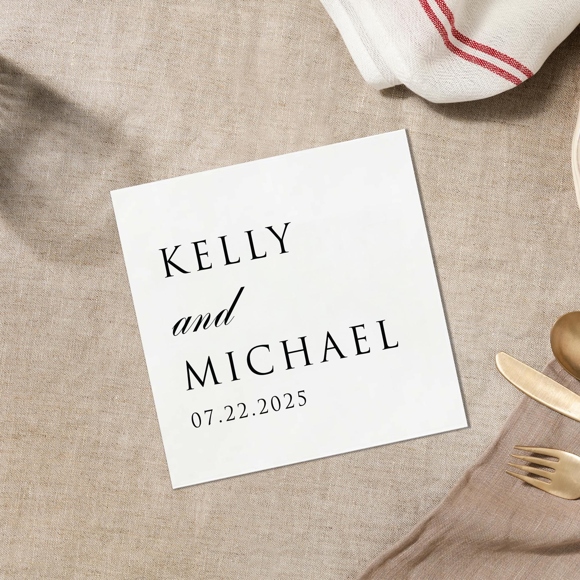 A white square card with black text is placed on a beige surface, along with a white napkin and a gold fork.