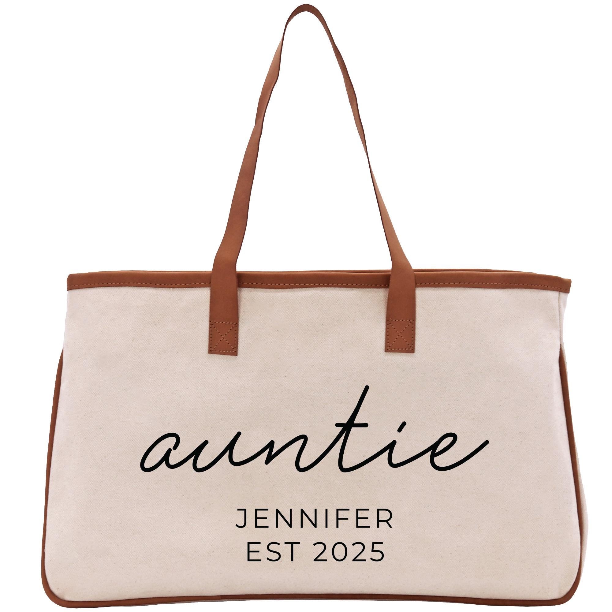 A beige canvas tote bag with brown straps and the text &quot;auntie&quot; printed on it.