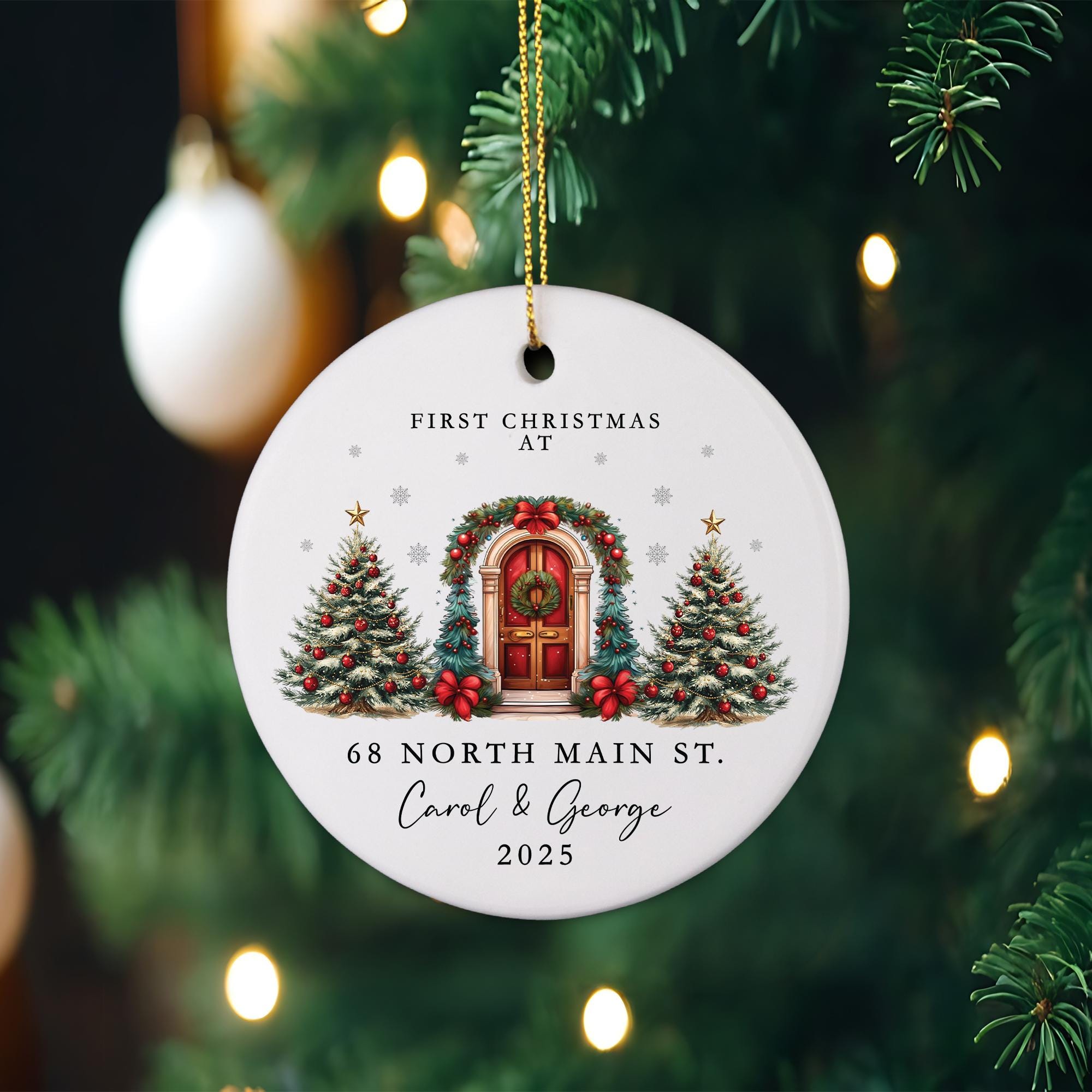 A white Christmas ornament with a wreath and a red door, hanging on a tree.