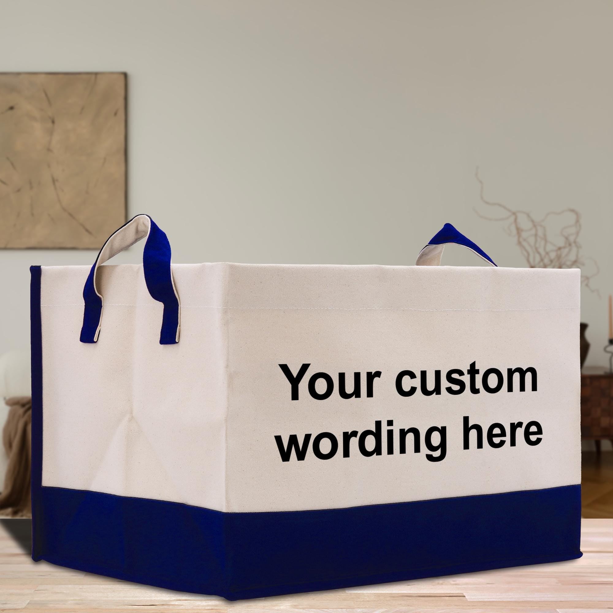 A white and blue tote bag with the text &quot;Your custom wording here&quot; printed on it, placed on a wooden surface.