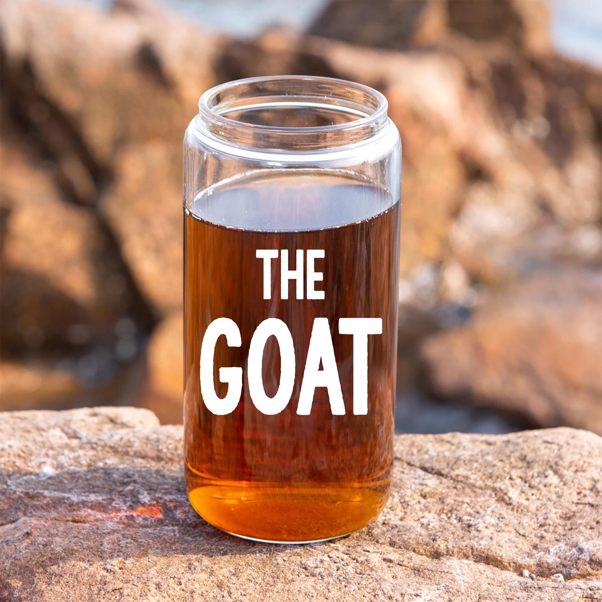 A glass jar filled with a brown liquid, placed on a rock.