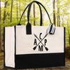 A black and white tote bag with a graphic design on it, placed on a wooden surface with a forest background.