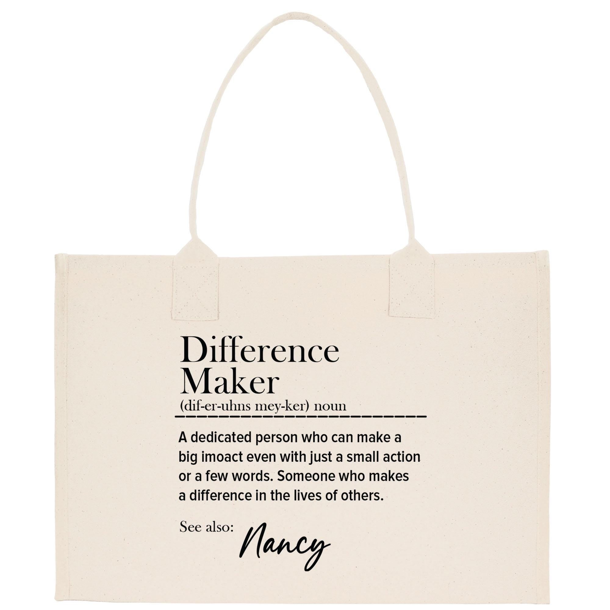 The image is a beige tote bag with a definition of a &quot; Difference Maker&quot; printed on it.