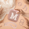 a woman's hand is holding a pink case with the letter m on it
