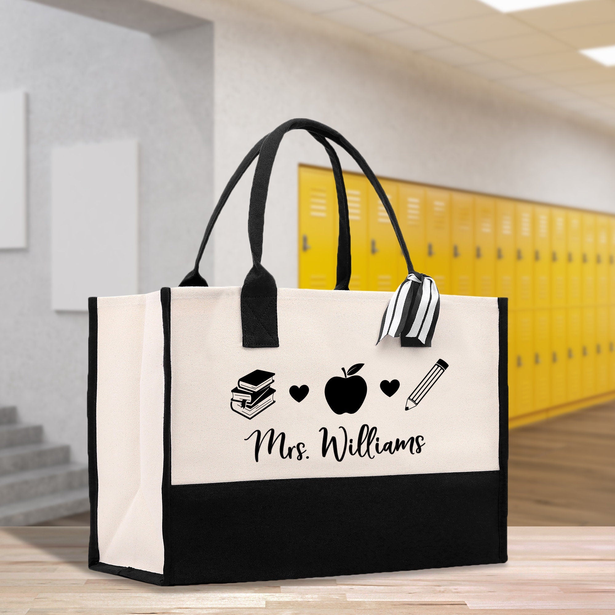 a black and white bag with a picture of a book, apple, and pencil