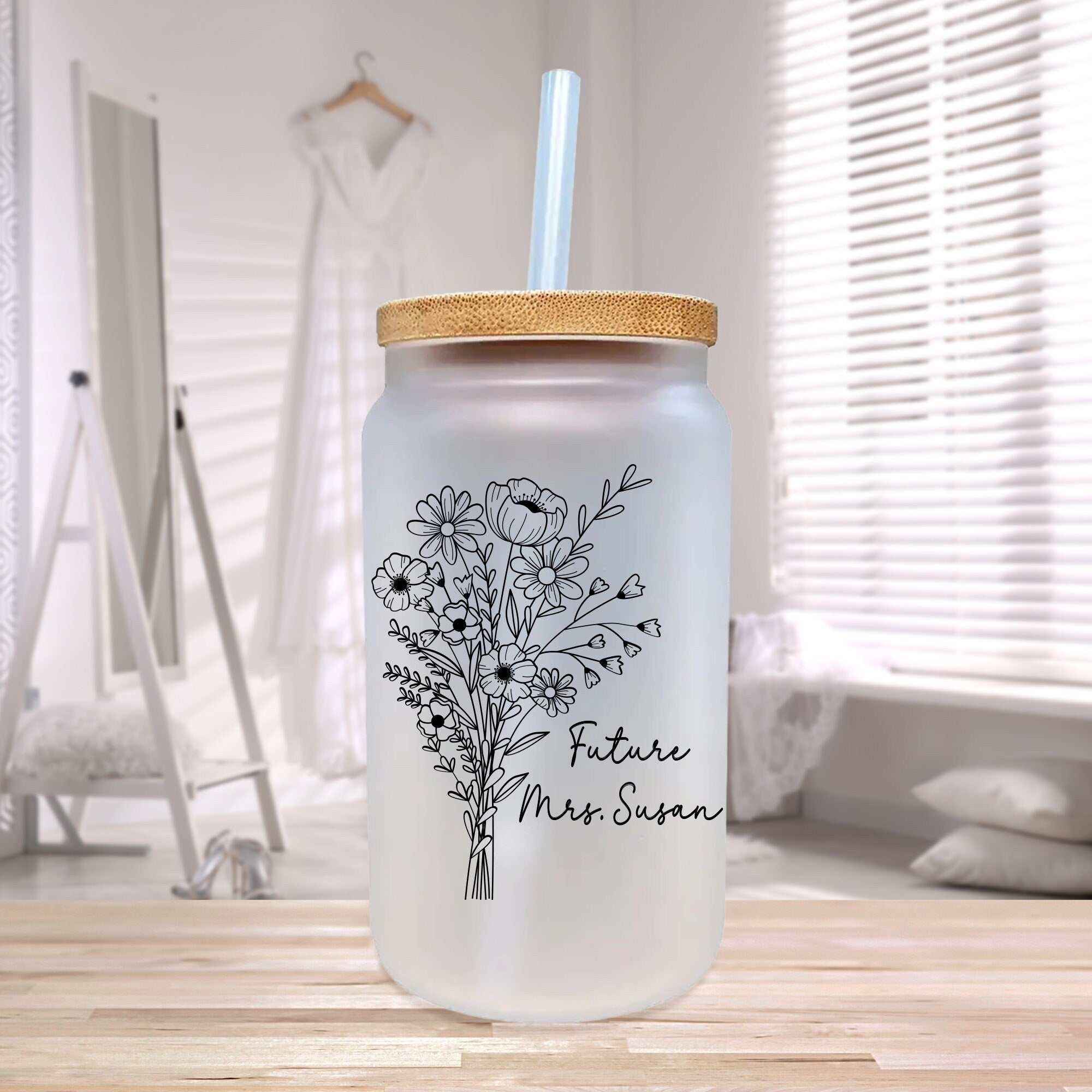 a mason jar with a straw lid and a flower design