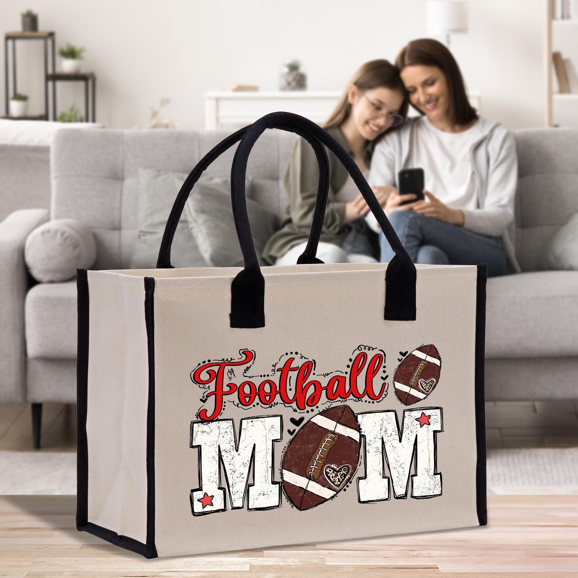 a woman sitting on a couch next to a bag with a football mom on it