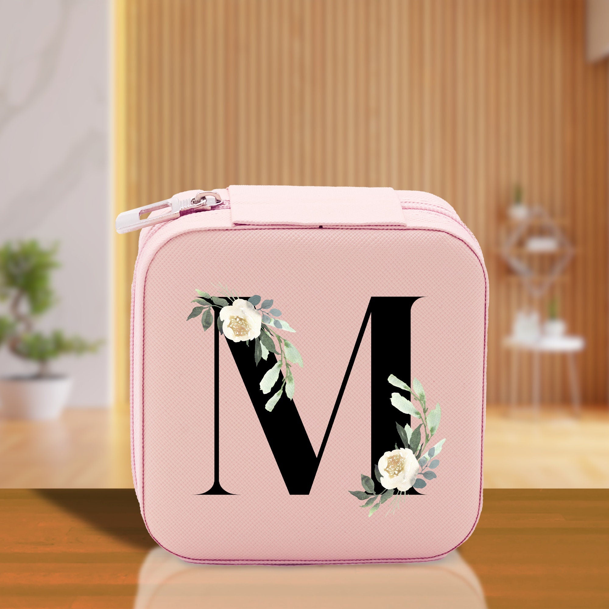 a pink lunch box with a monogrammed letter m on it